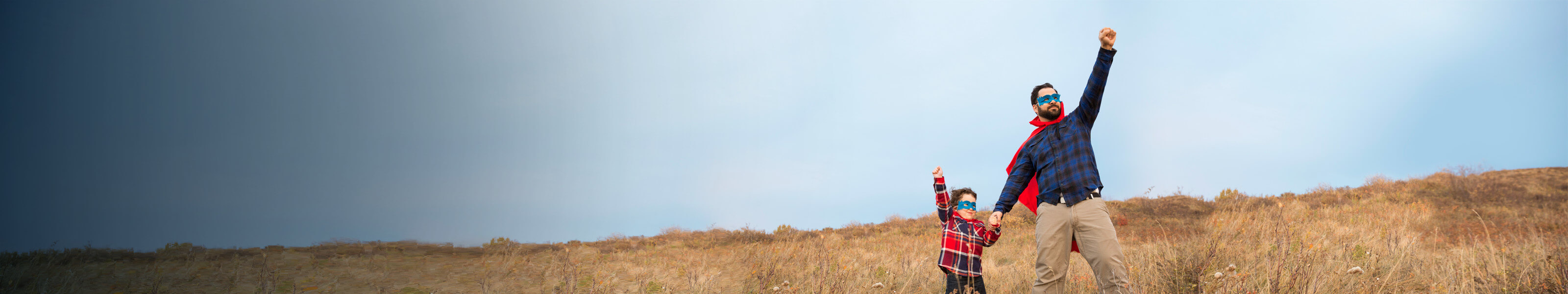 Father and son dressed as super heroes outside in a field