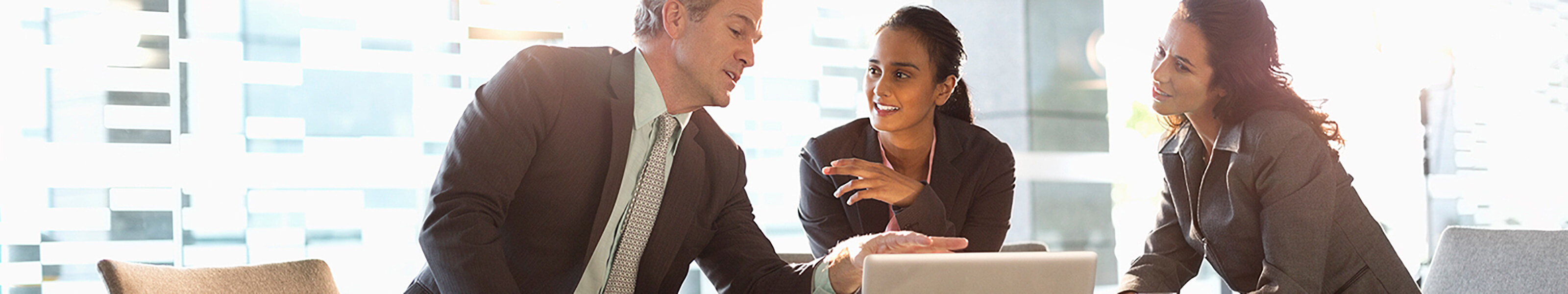 A businessman is in discussion with two businesswomen.