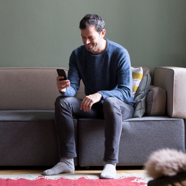 man sitting on couch looking at phone SunTrust Mobile App