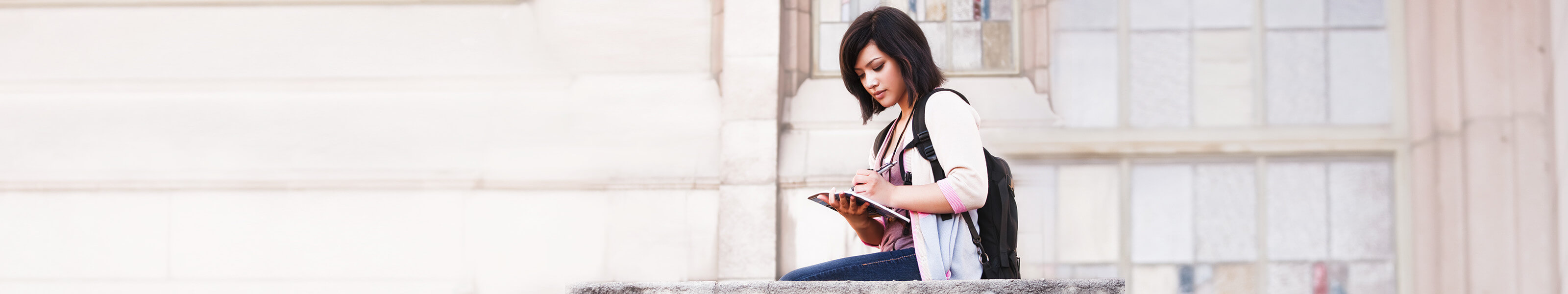 Female student writing in a notebook outside