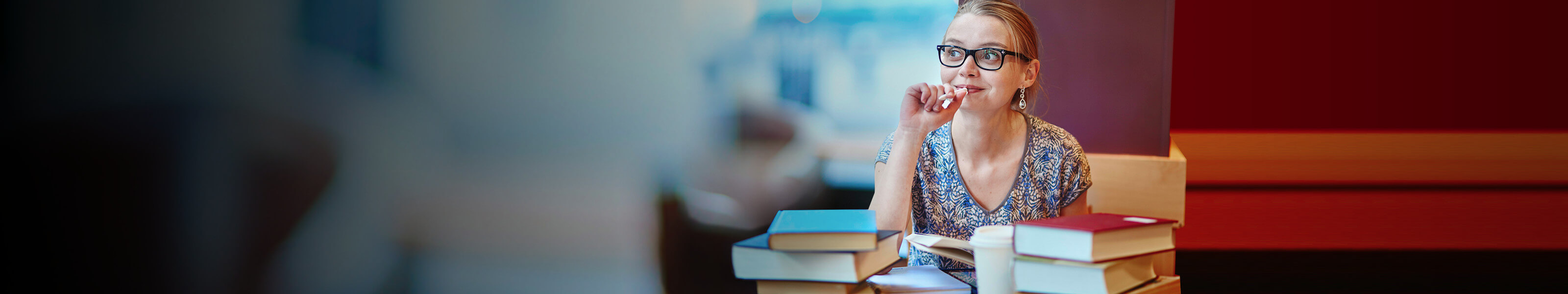 A young college-aged woman is sitting in library.
