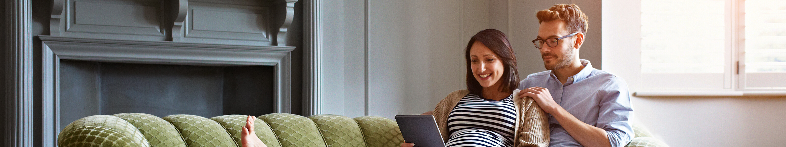expectant couple on couch viewing tablet