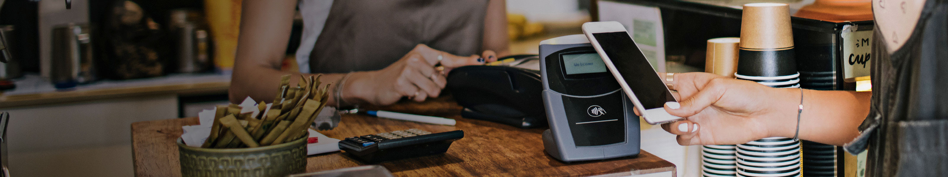 Billetera móvil y soluciones de pagos Cliente en mostrador de caja pagando sus compras con un teléfono móvil