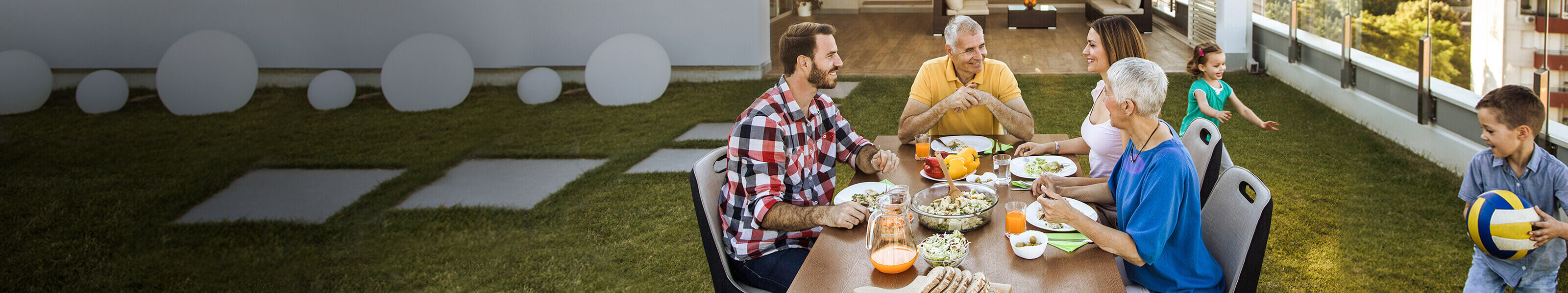 A family of five sits outdoors eating dinner.