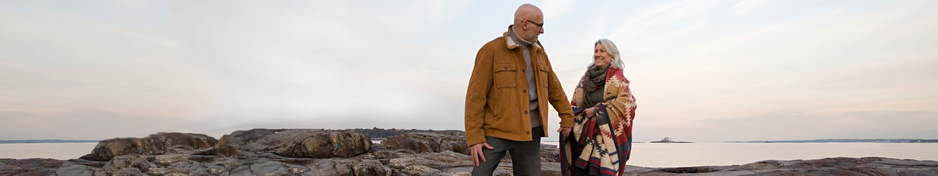 A senior couple walks on the beach.