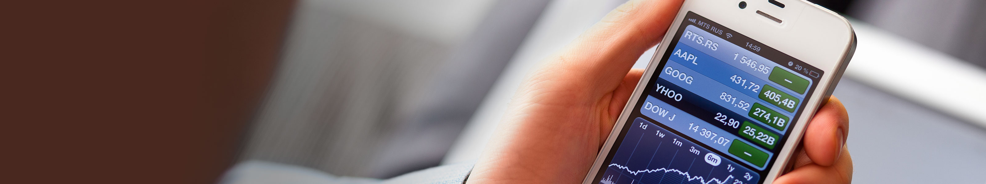 Close up of a hand holding a smart phone which is displaying stock information.