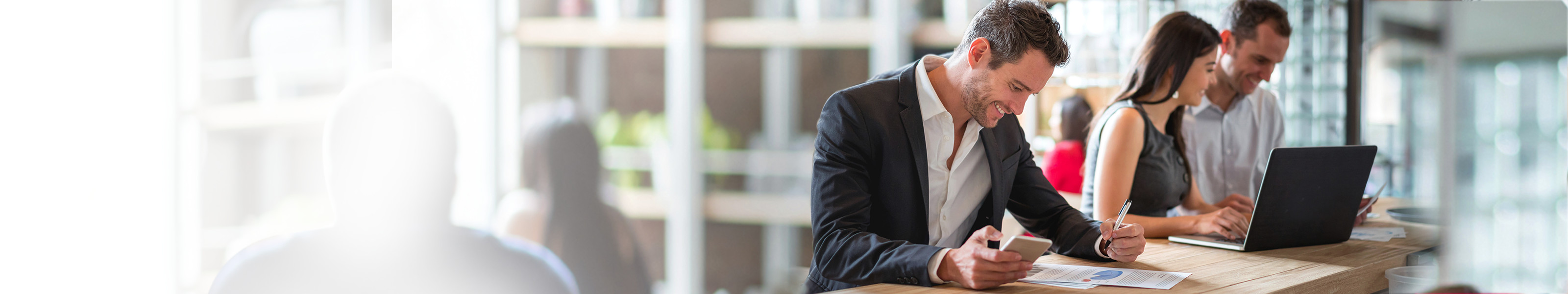 A middle-aged man is looking at paperwork while holding his mobile phone.