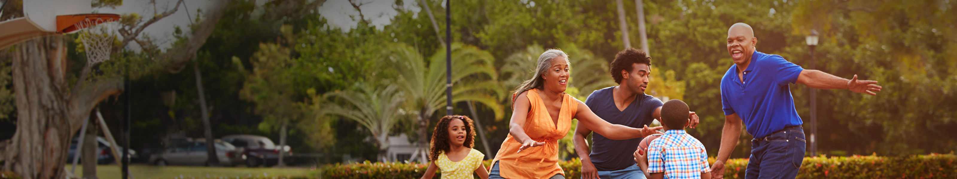 A multi-generational family plays basketball outdoors.
