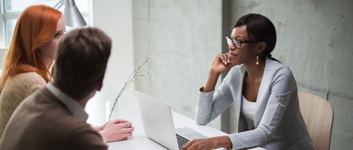 couple speaking with an advisor at a deask with laptop