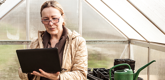 Woman in greenhouse on laptop, "Tips for a Flexible Retirement"