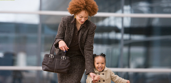 Working mother walking outside with smiling daughter